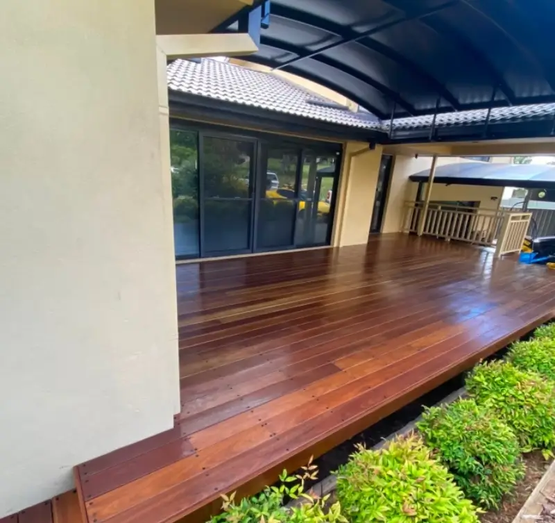 Covered outdoor timber deck with gabled roof, recessed lighting, and glass balustrade in Canberra.